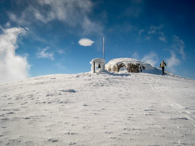 Reaching the peak of Psiloritis - Mt Ida - at Timios Stavros Cross and small chapel - a lone skier enjoys the bright blue day (image by Giorgos Spinthakis)