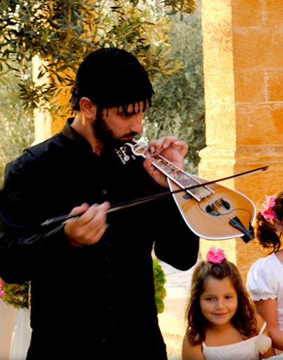 A Cretan man in traditional costume playing the lyra