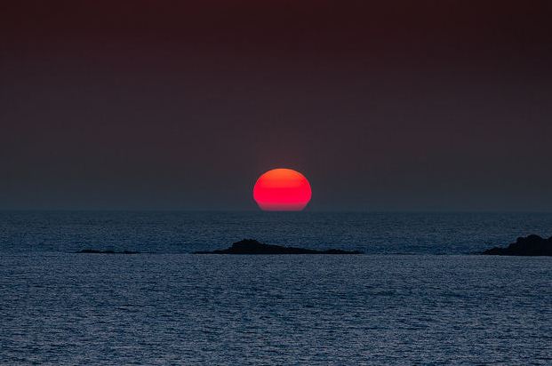 Φαλάσαρνα big red globe of the sun setting into the horizon (Image by Dieter Weinelt)