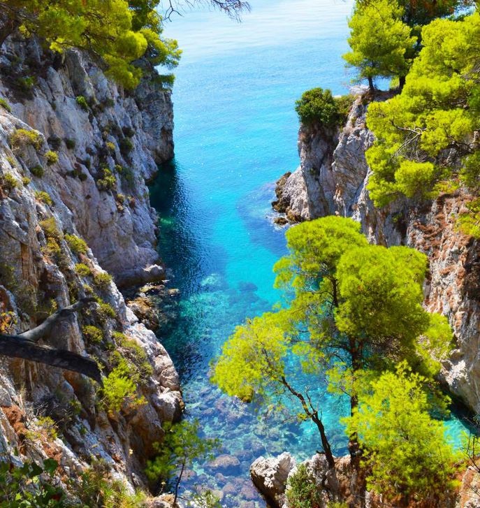 Aqua waters and treed cliffs form a miriad of colour in Skopelos