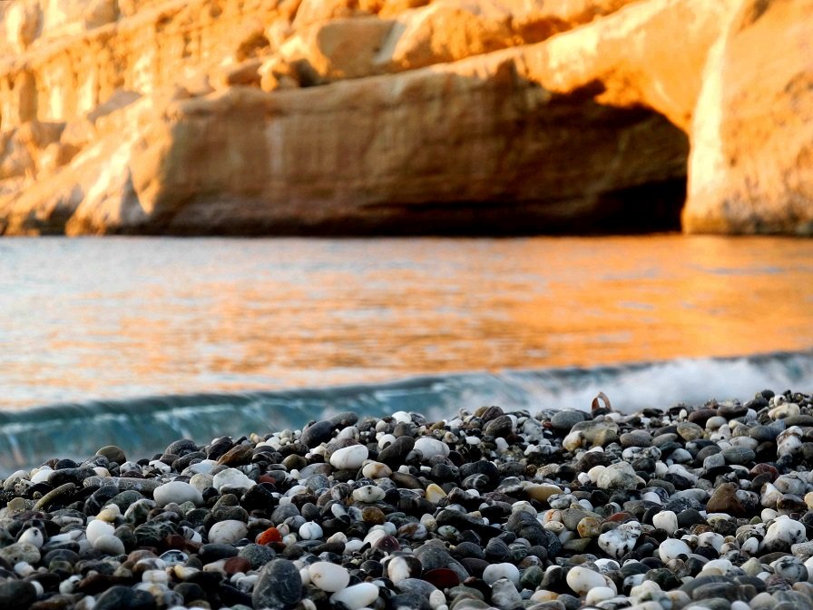 Matala Crete - the beach pebbles against the sea with the sun on the cave in the afternoon (image by Mark Latter)