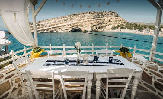 Scala fish taverna looks out across Matala Beach and over to the rocky peninsula and caves