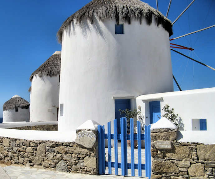 The windmills of Mykonos Chora are a bright blue and white against the elegant blue of the Med